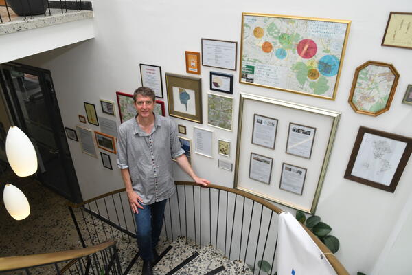 Künstler Daniel Hörnemann steht im Treppenhaus, dass er mit einer Collage geschmückt hat.