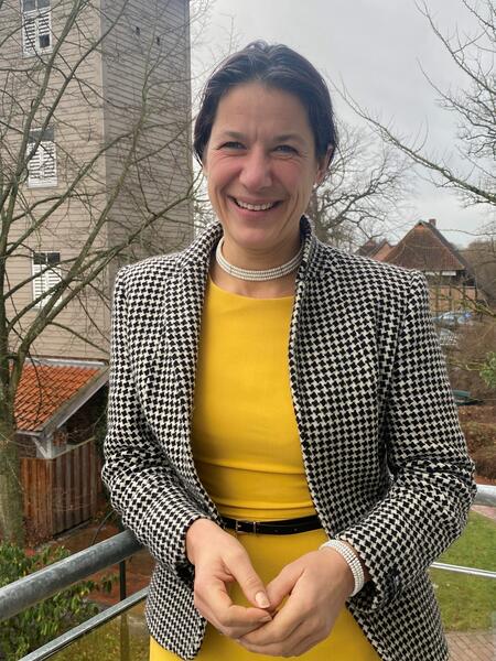 Bild vergrößern: Die Samtgemeindebürgermeisterin Claudia Sommer mit gelbem Kleid und schwarz-weiß gemustertem Blazer lächelt in die Kamera.