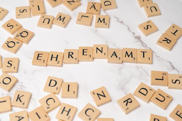 Das Wort EHRENAMT aus kleinen Holzplättchen mit jeweils einem Buchstaben gelegt.