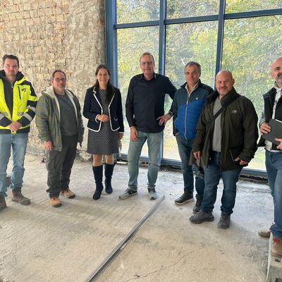 Bild vergr&ouml;&szlig;ern: Das Besprechungsteam bei der Baustellenbesichtigung blickt in die Kamera