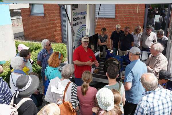 F&uuml;hrung durch das Kl&auml;rwerk am Tag der offenen T&uuml;r. Eine Gruppe von sommerlich gekleideten Menschen h&ouml;rt dem Kl&auml;rwerksleiter zu.