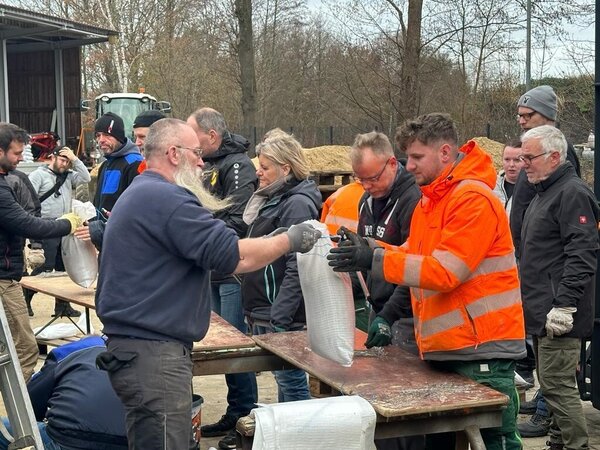 Bild vergr&ouml;&szlig;ern: Eine Gruppe von Menschen bef�llt Sands�cke.